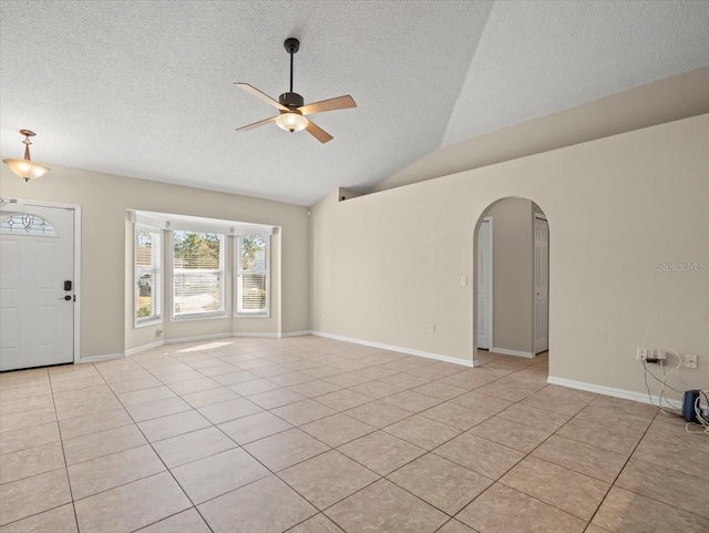 interior space featuring lofted ceiling, ceiling fan, light tile patterned flooring, and a textured ceiling