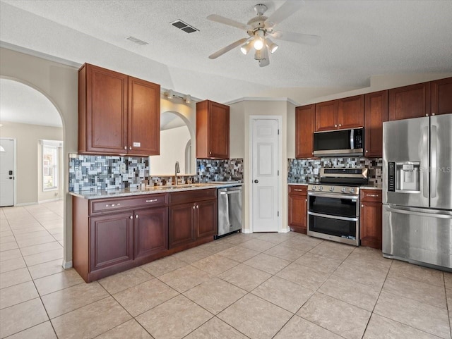 kitchen with tasteful backsplash, light tile patterned floors, appliances with stainless steel finishes, and sink