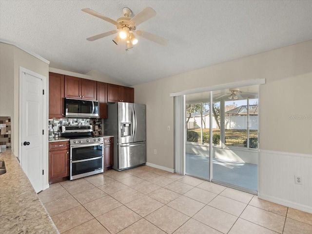 kitchen with lofted ceiling, light tile patterned flooring, stainless steel appliances, and a textured ceiling