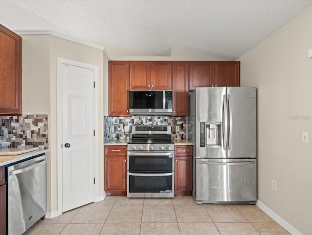 kitchen featuring light tile patterned floors, decorative backsplash, stainless steel appliances, and a textured ceiling