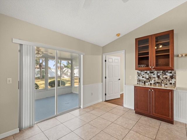 kitchen with lofted ceiling, light tile patterned floors, backsplash, and ceiling fan