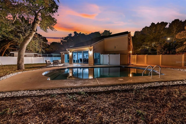 pool at dusk with a patio