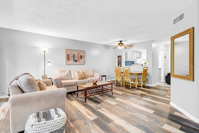 living room with hardwood / wood-style floors, a textured ceiling, and ceiling fan