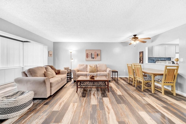 living room with ceiling fan, hardwood / wood-style floors, and a textured ceiling