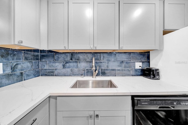 kitchen featuring light stone counters, sink, white cabinetry, and dishwasher