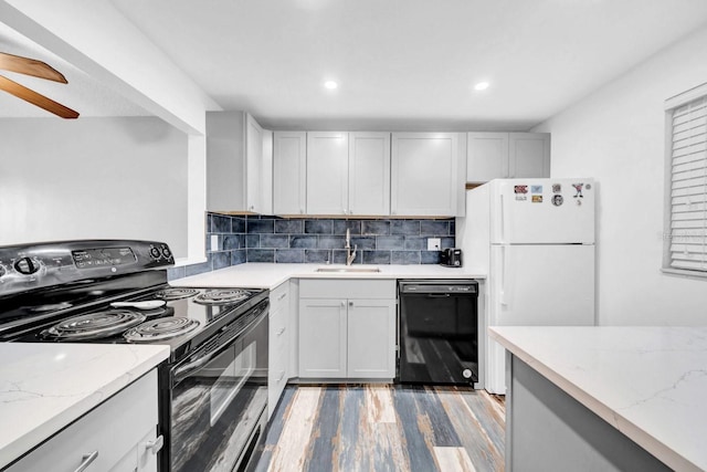 kitchen featuring dark hardwood / wood-style floors, sink, decorative backsplash, light stone counters, and black appliances