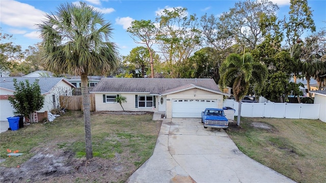 ranch-style house featuring an attached garage, driveway, fence, and a front yard