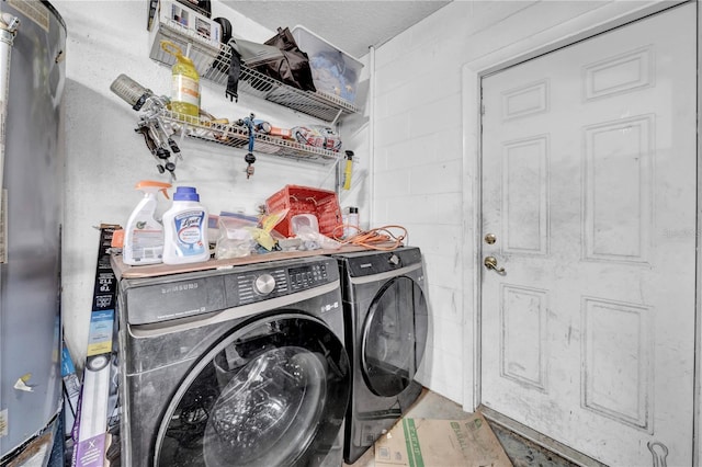 clothes washing area with a textured ceiling, water heater, and washing machine and clothes dryer