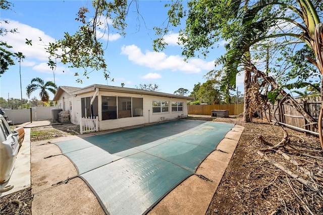 back of house featuring a patio, a sunroom, and a covered pool