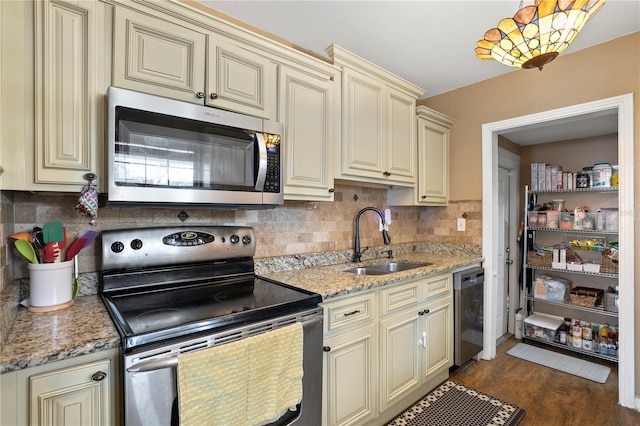 kitchen featuring dark hardwood / wood-style floors, sink, light stone counters, stainless steel appliances, and cream cabinetry