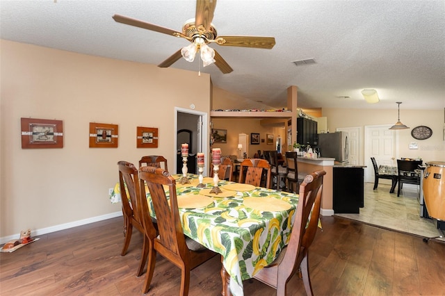 dining space with lofted ceiling, ceiling fan, dark wood-type flooring, and a textured ceiling