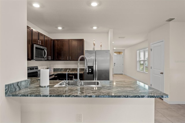 kitchen featuring kitchen peninsula, dark stone counters, dark brown cabinetry, and stainless steel appliances