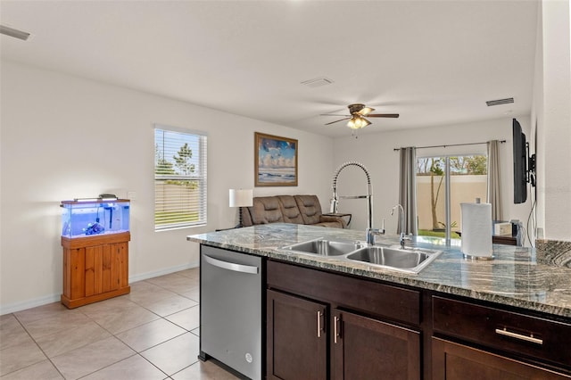 kitchen featuring dishwasher, dark stone counters, sink, light tile patterned floors, and dark brown cabinets