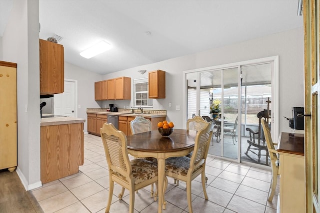 tiled dining space featuring sink and vaulted ceiling