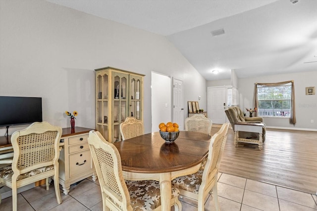 dining area with vaulted ceiling and light tile patterned floors