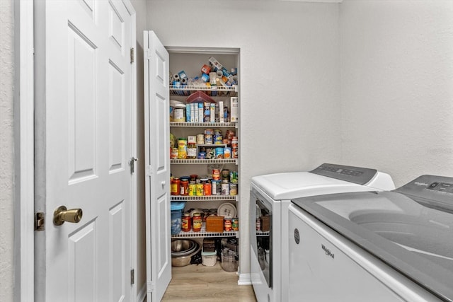 clothes washing area featuring separate washer and dryer and light hardwood / wood-style floors