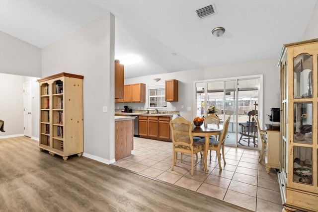 kitchen with lofted ceiling, sink, stainless steel dishwasher, and light hardwood / wood-style floors