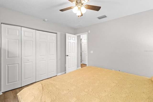 unfurnished bedroom with wood-type flooring, ceiling fan, and a closet