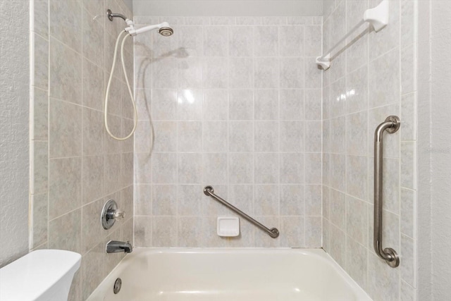 bathroom with tiled shower / bath and toilet