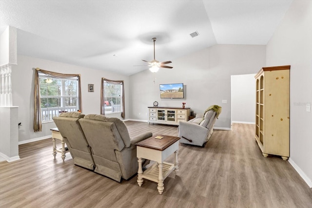 living room featuring ceiling fan, lofted ceiling, and light wood-type flooring