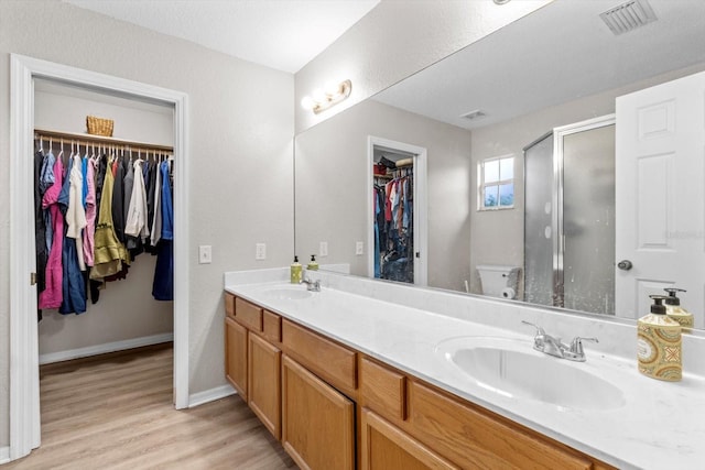 bathroom with vanity, toilet, a shower with door, and hardwood / wood-style floors