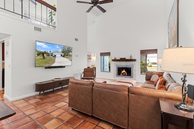 living room featuring ceiling fan, tile patterned flooring, a fireplace, and a high ceiling