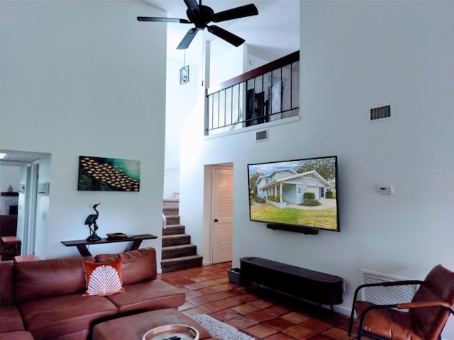 tiled living area with a towering ceiling, stairs, and a ceiling fan