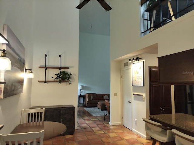 dining room featuring a high ceiling, a ceiling fan, and baseboards