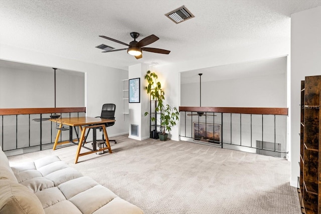 carpeted living room with ceiling fan, an office area, a textured ceiling, and baseboards