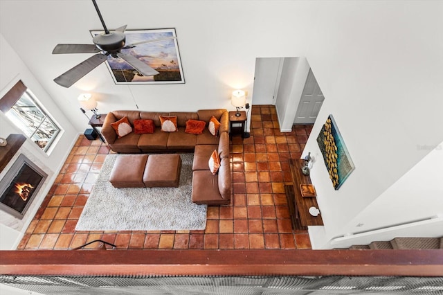 living room featuring ceiling fan and a glass covered fireplace