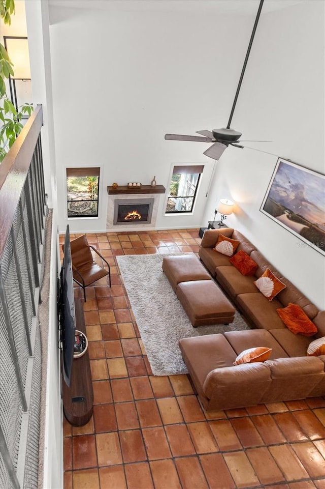 tiled living area featuring a fireplace with flush hearth and a ceiling fan