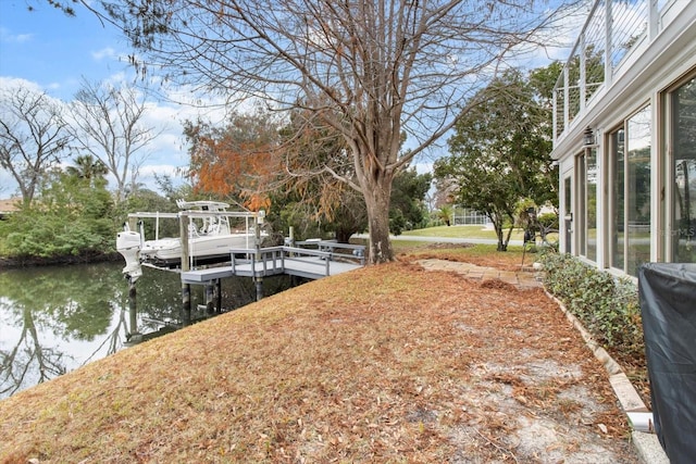 view of yard featuring a water view, a boat dock, and boat lift