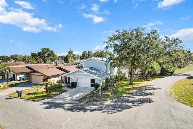 view of front facade with concrete driveway, an attached garage, a front lawn, and a residential view