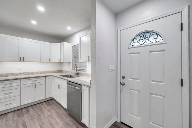 kitchen featuring sink, white cabinetry, light stone counters, light wood-type flooring, and stainless steel dishwasher