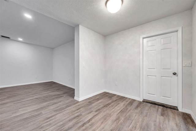 bonus room with a textured ceiling and light hardwood / wood-style flooring