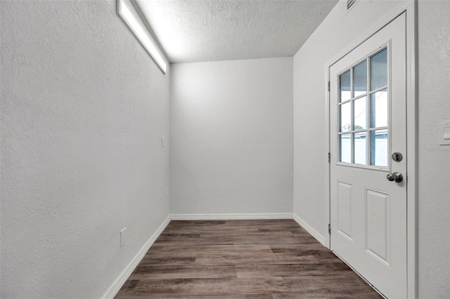 doorway to outside with dark hardwood / wood-style floors and a textured ceiling