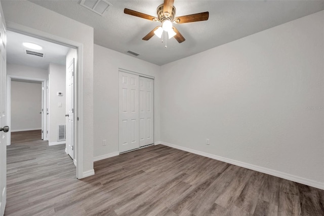 unfurnished bedroom with light hardwood / wood-style flooring, a closet, and ceiling fan