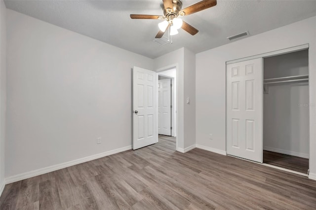 unfurnished bedroom featuring a textured ceiling, light hardwood / wood-style flooring, a closet, and ceiling fan