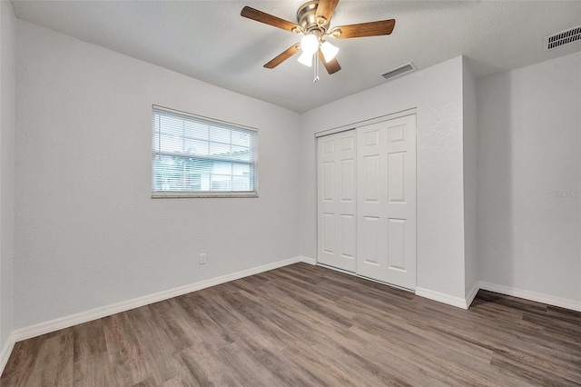 unfurnished bedroom featuring dark hardwood / wood-style flooring, a closet, and ceiling fan