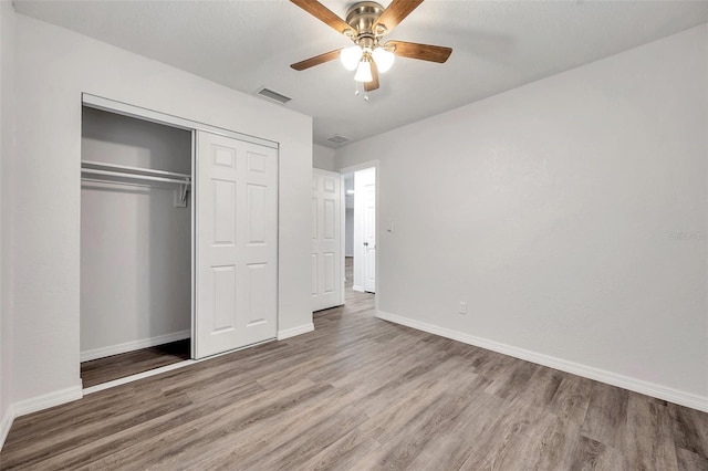 unfurnished bedroom featuring ceiling fan, wood-type flooring, and a closet