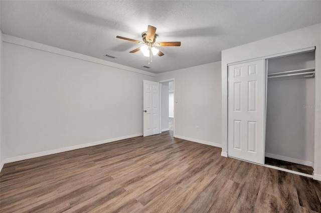 unfurnished bedroom featuring wood-type flooring, a textured ceiling, ceiling fan, and a closet