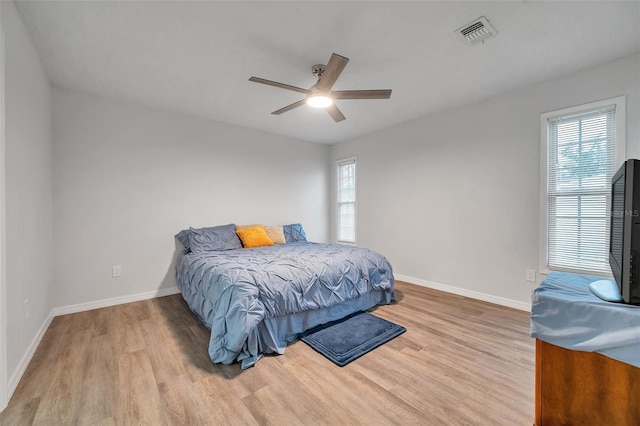 bedroom featuring multiple windows, wood-type flooring, and ceiling fan