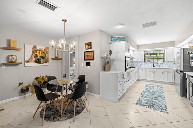 dining room with sink, a textured ceiling, light tile patterned floors, and a chandelier