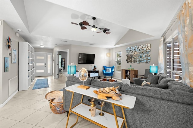 tiled living room with ceiling fan and a tray ceiling