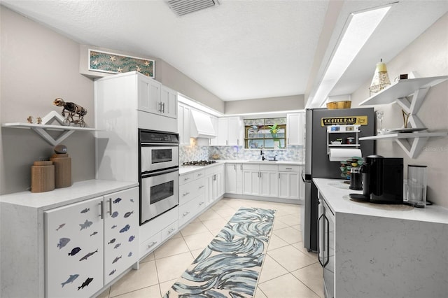 kitchen featuring sink, backsplash, white cabinets, a textured ceiling, and stainless steel appliances