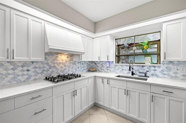 kitchen featuring sink, backsplash, white cabinets, and premium range hood