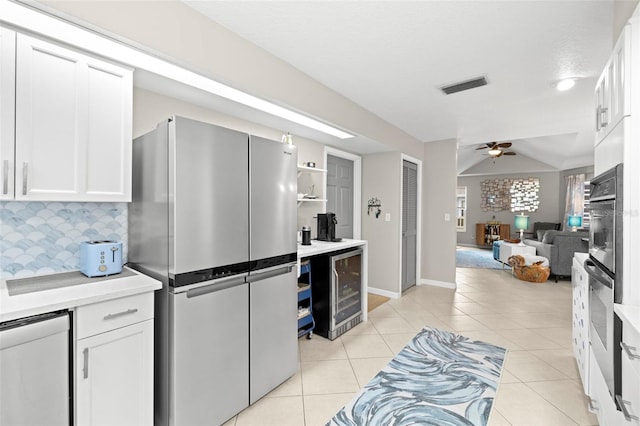 kitchen featuring white cabinets, wall oven, stainless steel fridge, and wine cooler