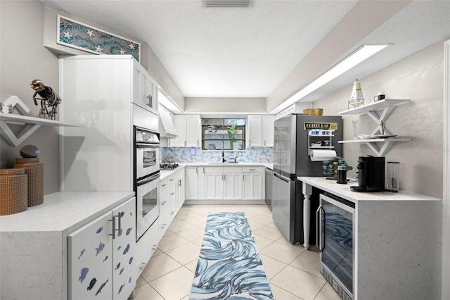 kitchen with wine cooler, premium range hood, white cabinetry, light tile patterned flooring, and stainless steel appliances