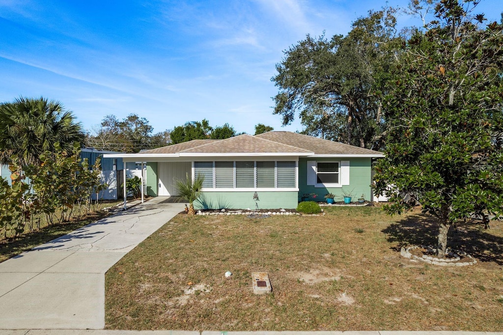 ranch-style house featuring a carport and a front lawn