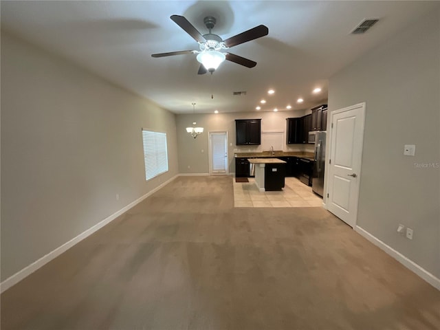 kitchen with sink, a center island, light carpet, stainless steel fridge, and ceiling fan with notable chandelier